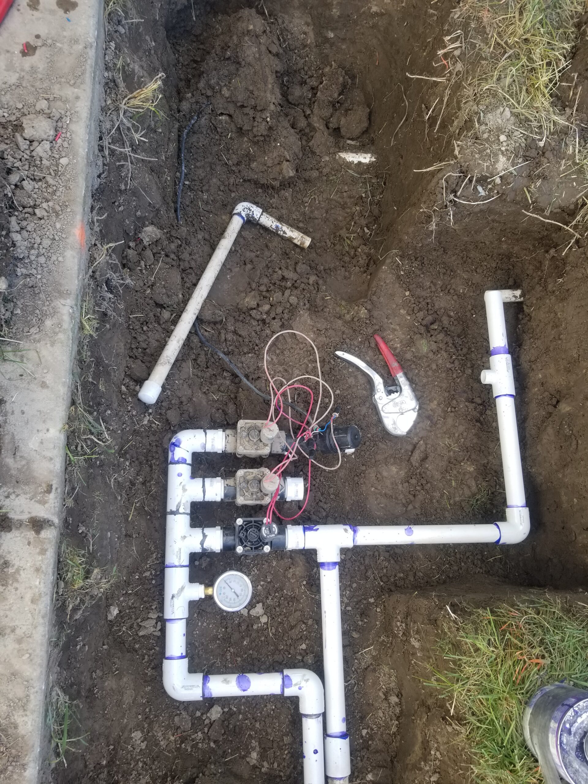 PVC irrigation repair with valves and pressure gauge in trench