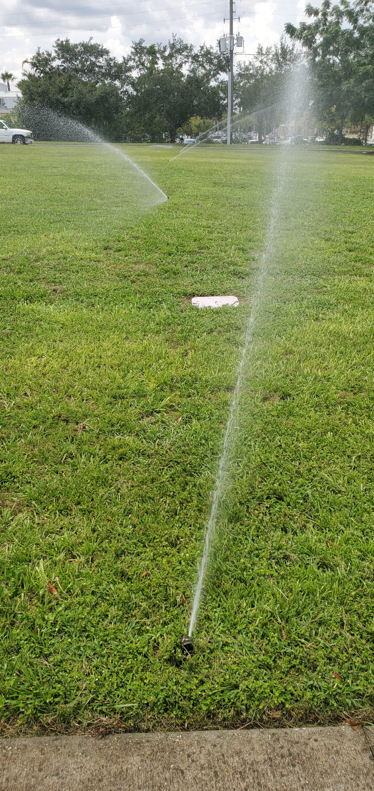 Sprinkler spraying across a green lawn during irrigation service