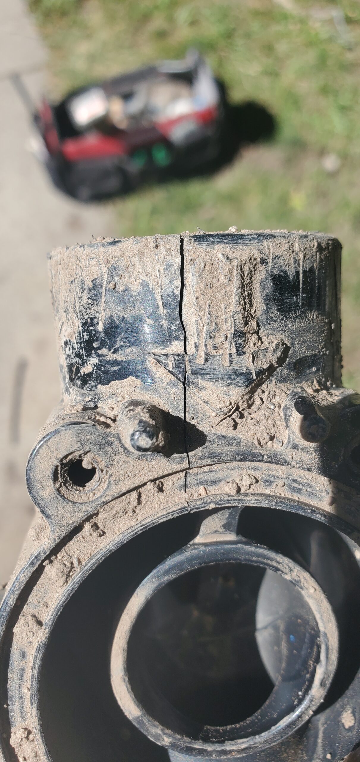Close-up of a cracked irrigation pipe fitting during repair work