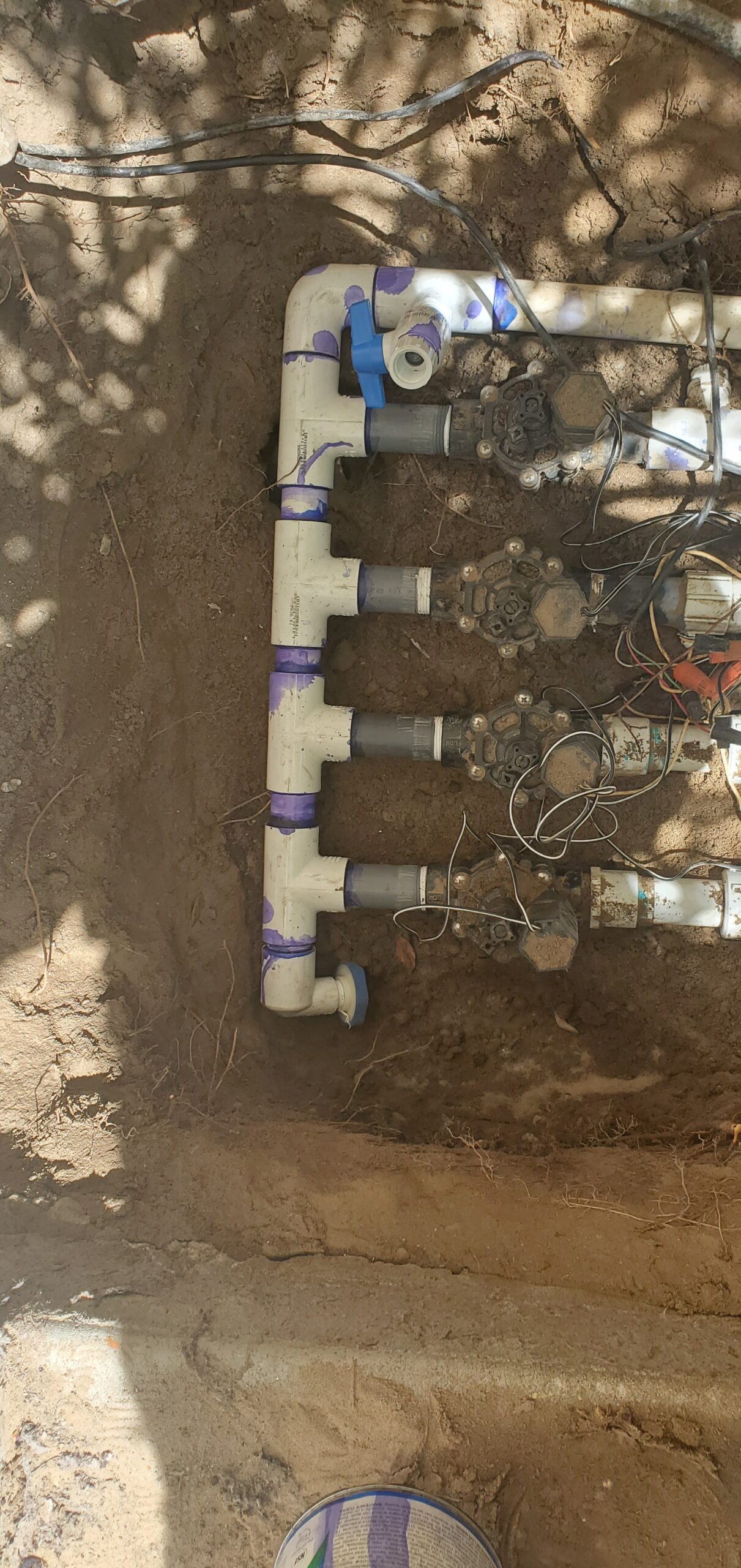 Underground irrigation valve and PVC pipe assembly with wiring along a dirt wall