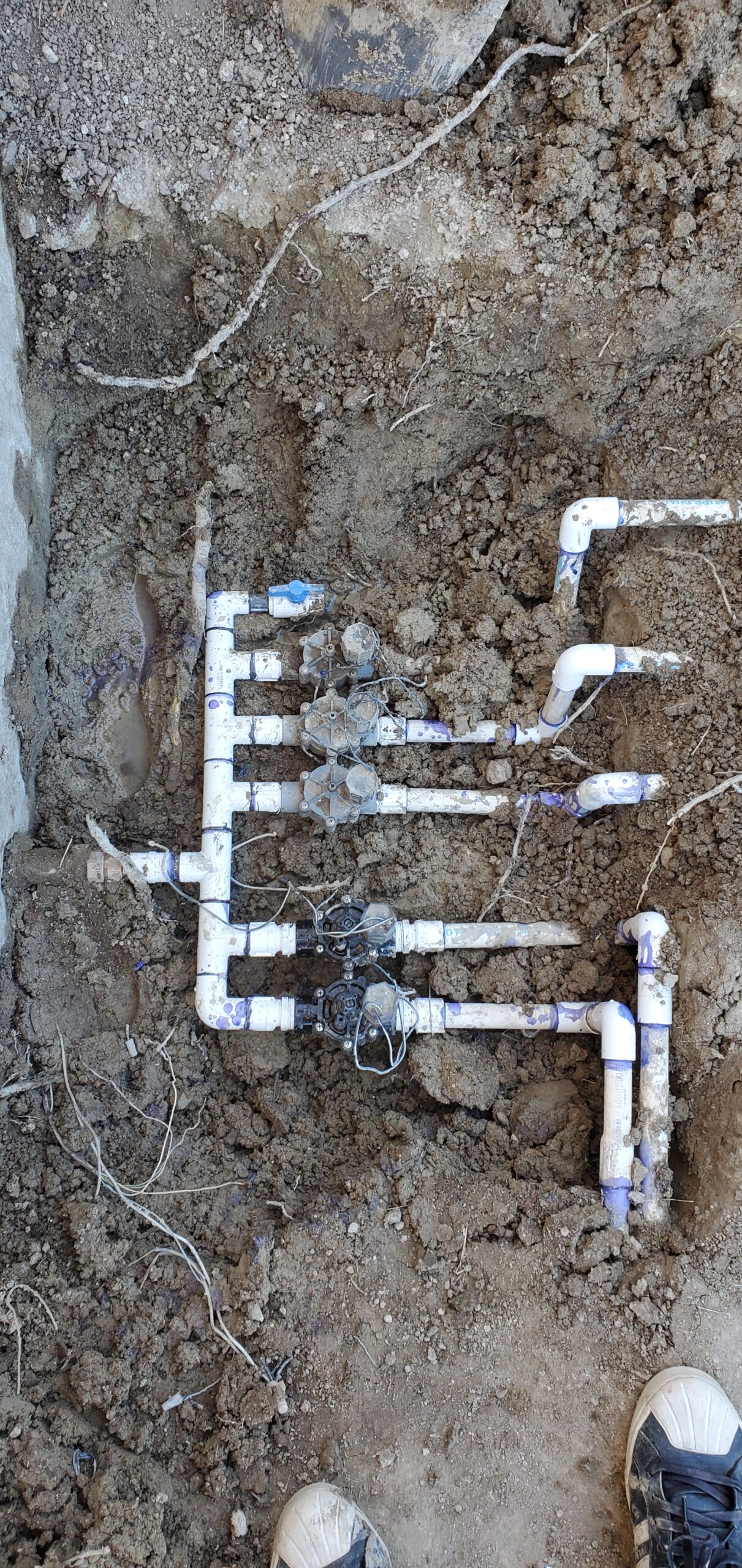 Irrigation valves and PVC pipes exposed in an excavation pit