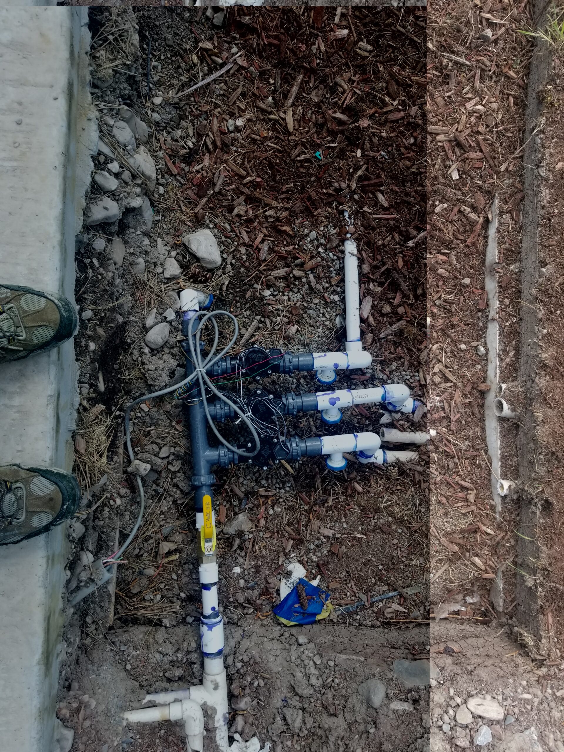 Irrigation valve manifold with PVC pipes and wiring in a trench
