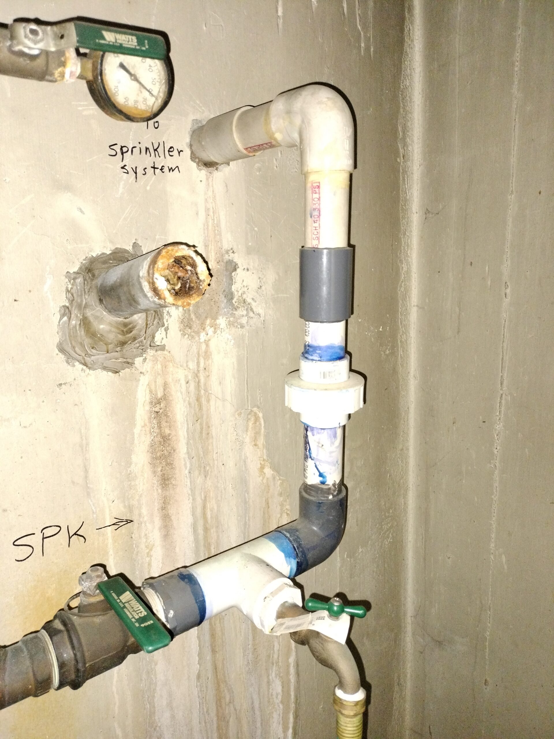Sprinkler system pipe installation mounted on a concrete wall with labeled lines
