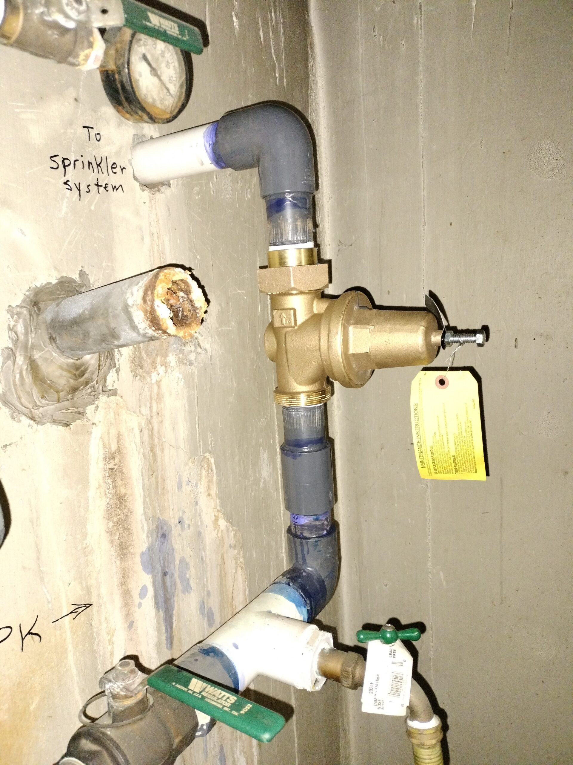 Brass irrigation valve assembly mounted on a wall with sprinkler system piping