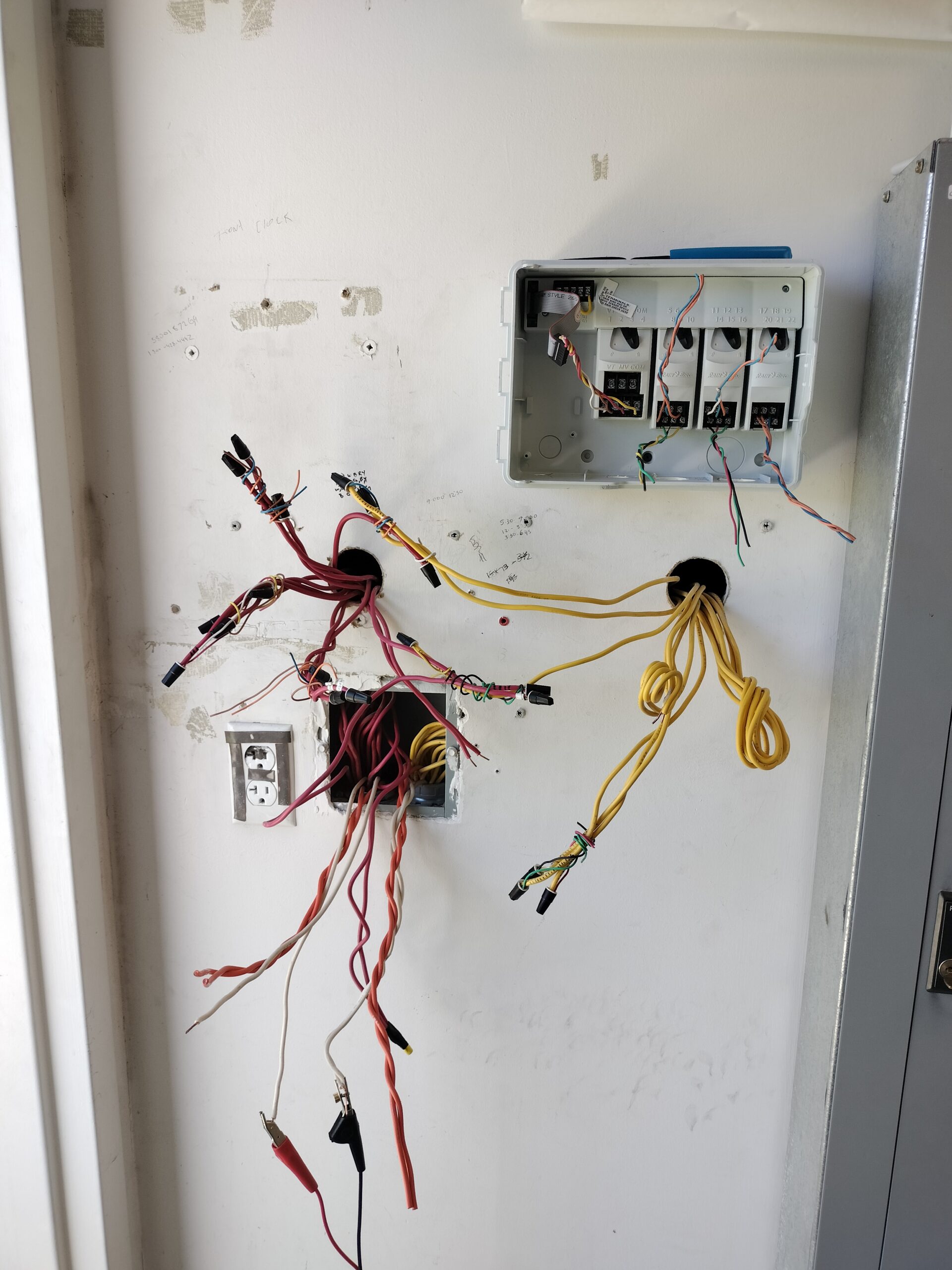 Open irrigation controller panel with exposed wiring on a wall