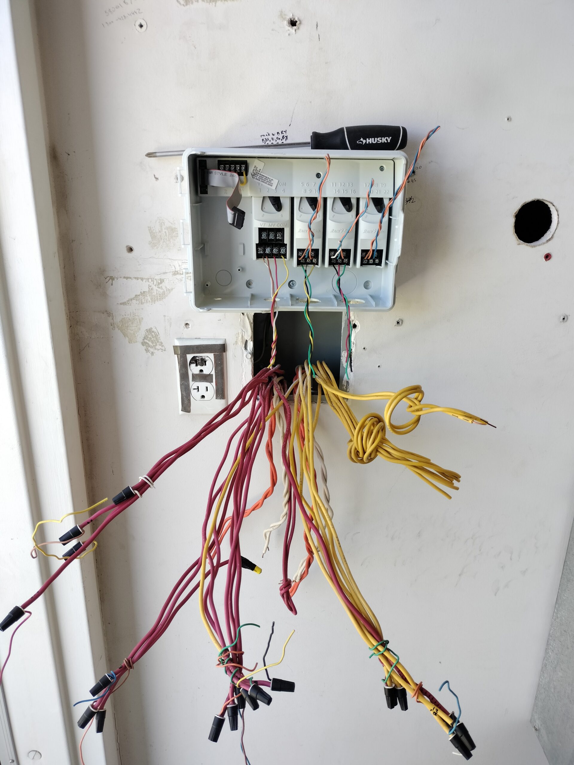 Open irrigation control box with multicolored wiring on a wall