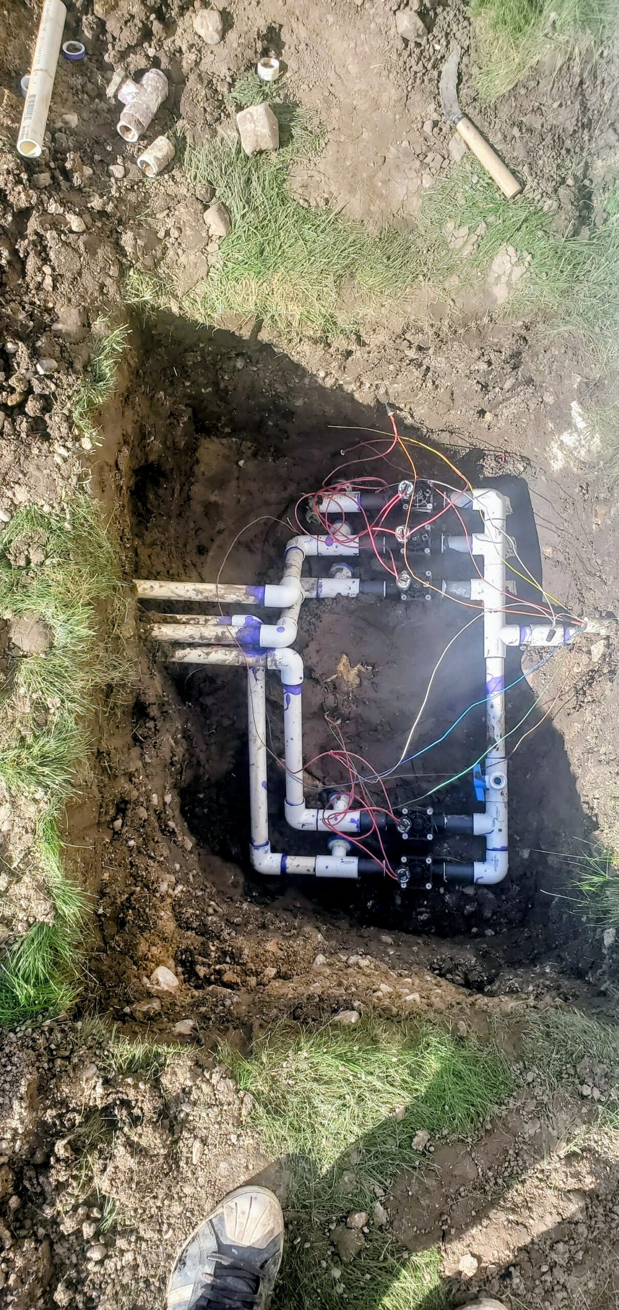 Buried irrigation plumbing system with wiring in an excavation pit